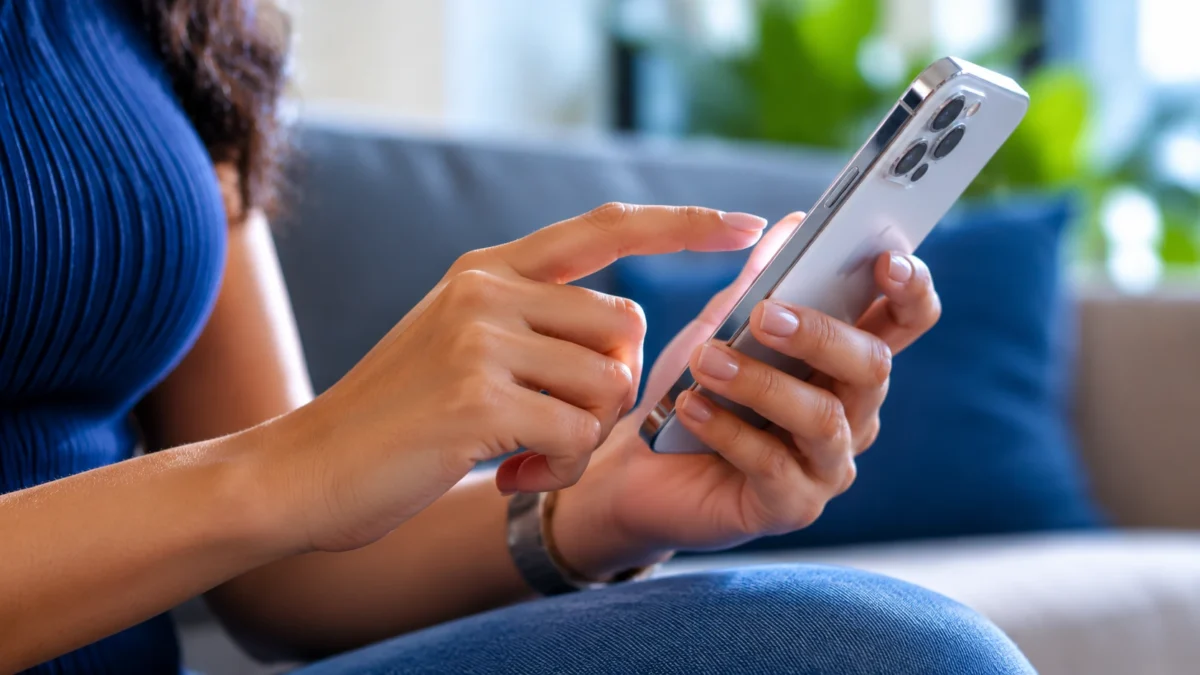 Pessoa utilizando iPhone para acessar as configurações e ativar o recurso de chamada de emergência.