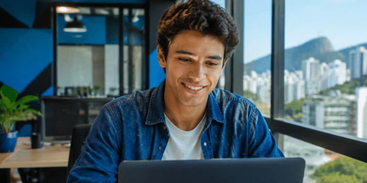 Jovem profissional utilizando notebook em escritório moderno, representando oportunidades de estágio, jovem aprendiz e trainee no Rio de Janeiro.