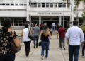 Pessoas caminham em direção a uma prefeitura municipal durante período de inscrições para concursos públicos.