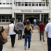 Pessoas caminham em direção a uma prefeitura municipal durante período de inscrições para concursos públicos.