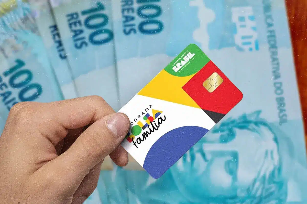 Valores do Bolsa Família em agosto de 2026 Mão segura o cartão do Bolsa Família diante de notas de real, representando os valores pagos pelo programa em agosto de 2026.