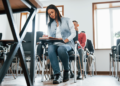 Jovens concentrados realizando prova em sala de aula iluminada.