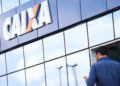 Fachada da agência Caixa Econômica Federal com homem chegando.