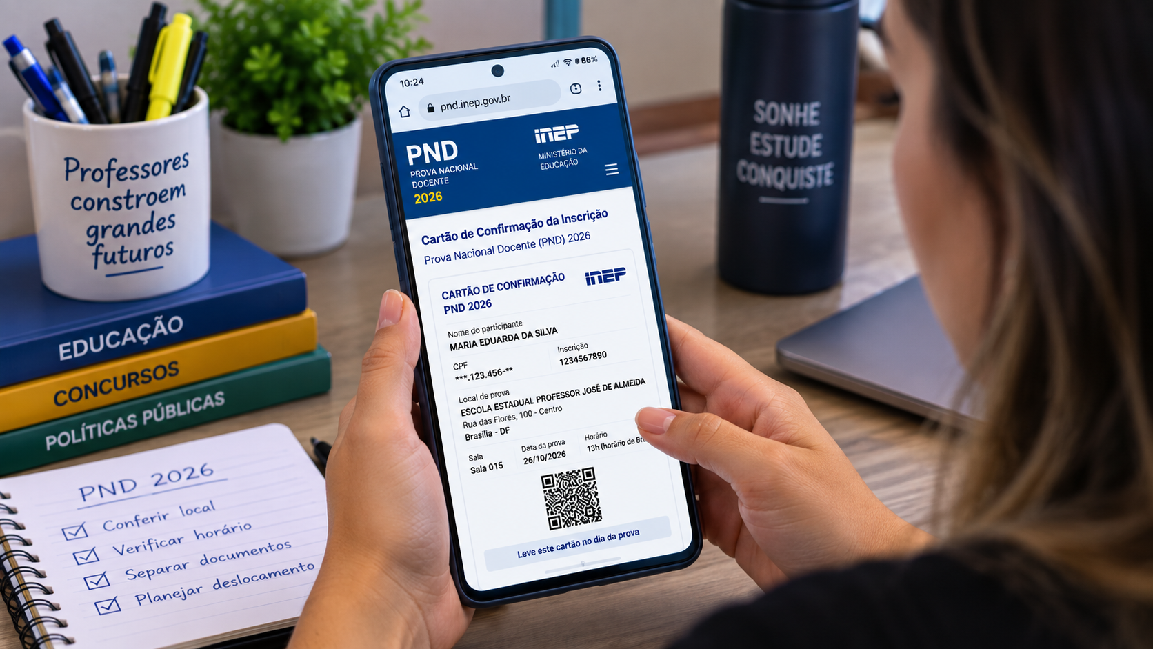 Mulher consulta cartão de confirmação da PND 2026 no celular ao lado de checklist, livros e caneca.