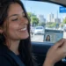 Jovem brasileira segura carteira de habilitação dentro de um carro, representando o aumento da busca pela primeira habilitação e as mudanças promovidas pela CNH do Brasil.