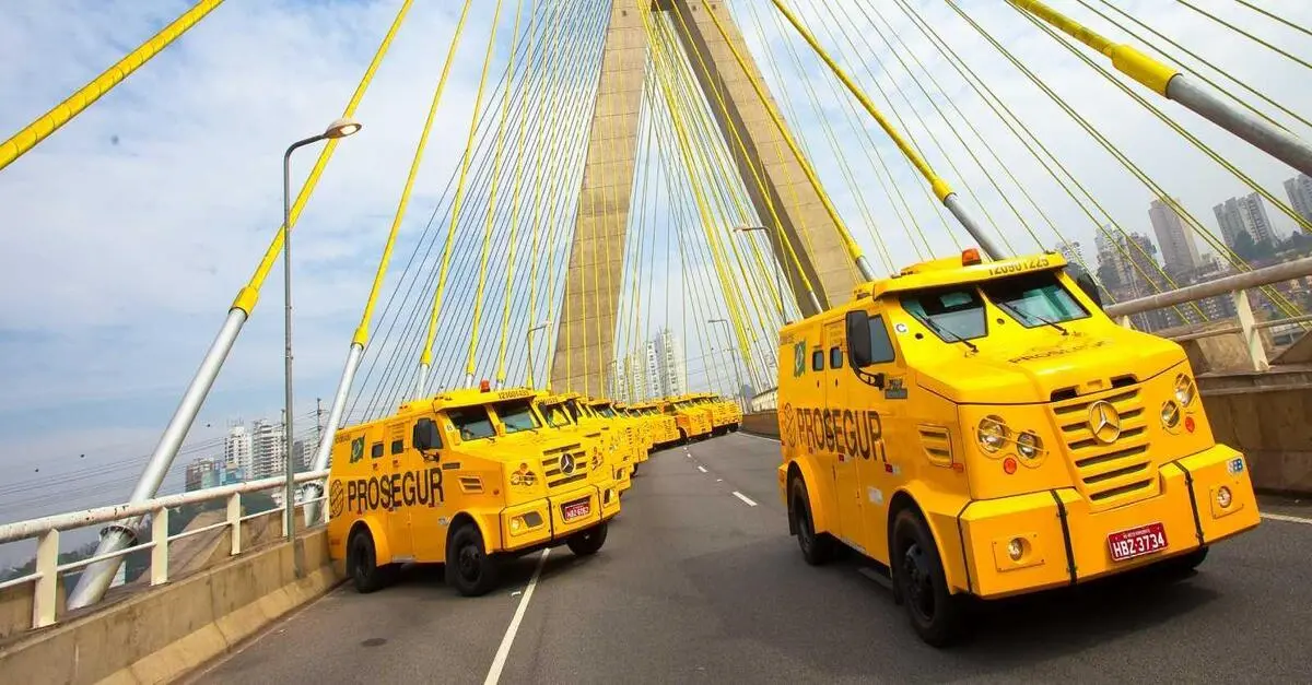 Carros-fortes blindados realizando transporte de valores em uma ponte urbana.