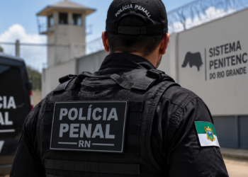 Policial penal do Rio Grande do Norte em frente a unidade prisional representando concurso público da Polícia Penal-RN.