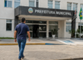 Pessoa caminhando em direção à Prefeitura Municipal de Santana do Mundaú, representando o concurso público com 101 vagas e salários de até R$ 8.354.