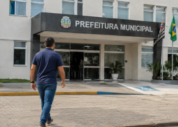 Pessoa caminhando em direção à Prefeitura Municipal de Santana do Mundaú, representando o concurso público com 101 vagas e salários de até R$ 8.354.