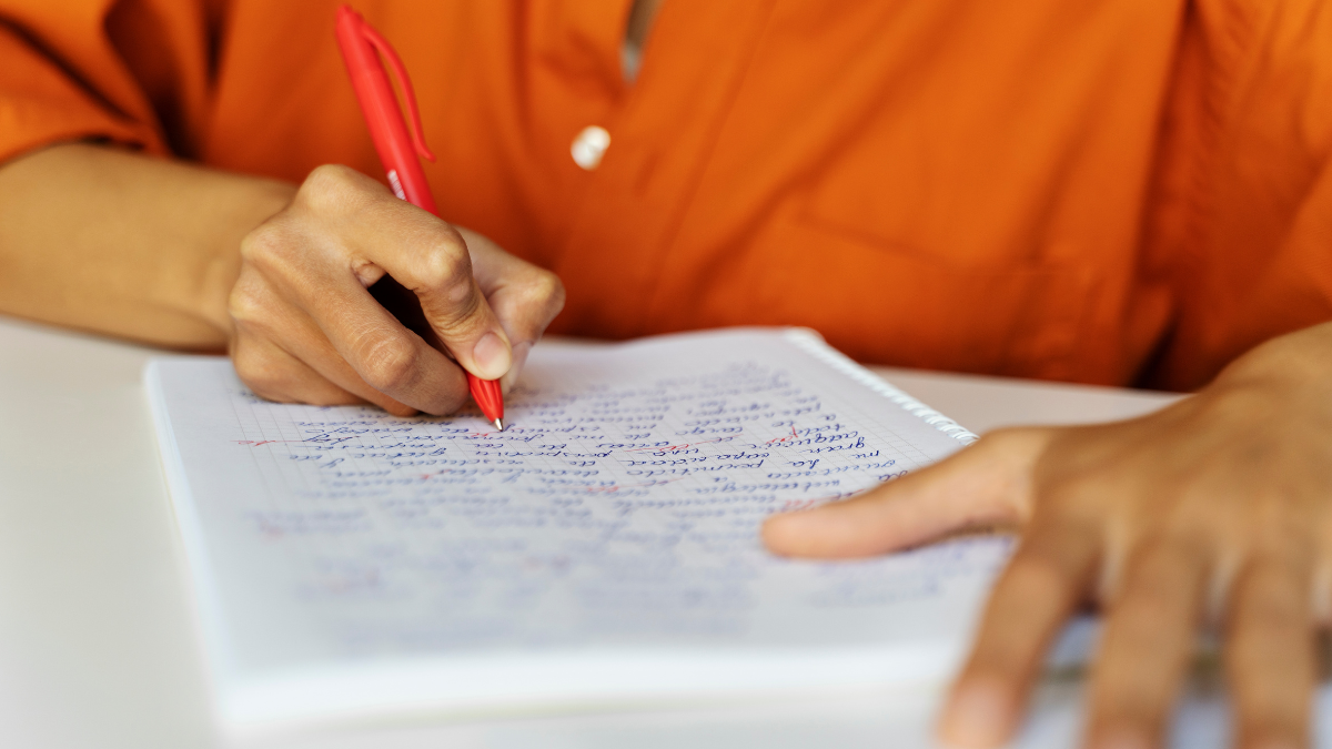 Pessoa fazendo anotações em caderno, representando preparação para concursos de câmaras municipais.