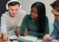 Pessoas estudando e se preparando para concursos públicos com materiais de estudo sobre a mesa.