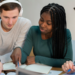 Pessoas estudando e se preparando para concursos públicos com materiais de estudo sobre a mesa.