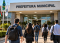 Pessoas caminhando em direção a uma prefeitura municipal representando concursos públicos com vagas abertas em municípios do Sul do Brasil.