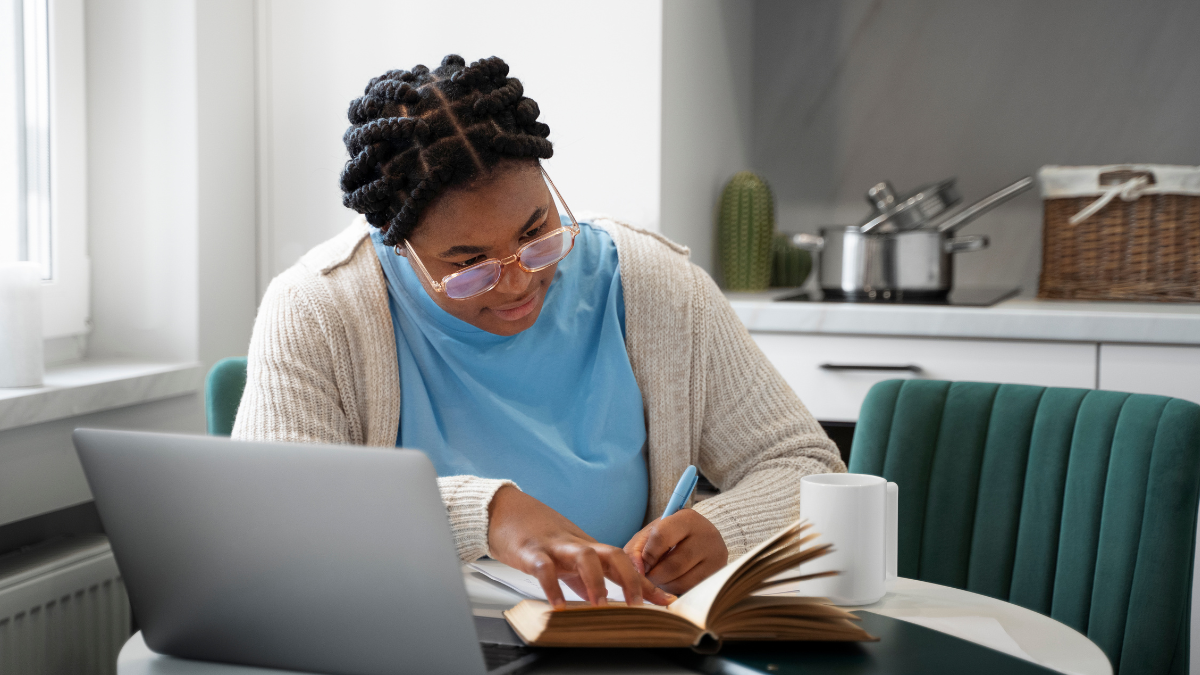 Pessoa estudando com notebook e livros para preparação para concursos públicos.