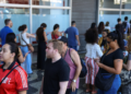 Pessoas em fila para atendimento, representando candidatos em busca de oportunidades em concursos públicos.