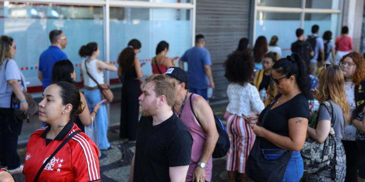 Pessoas em fila para atendimento, representando candidatos em busca de oportunidades em concursos públicos.