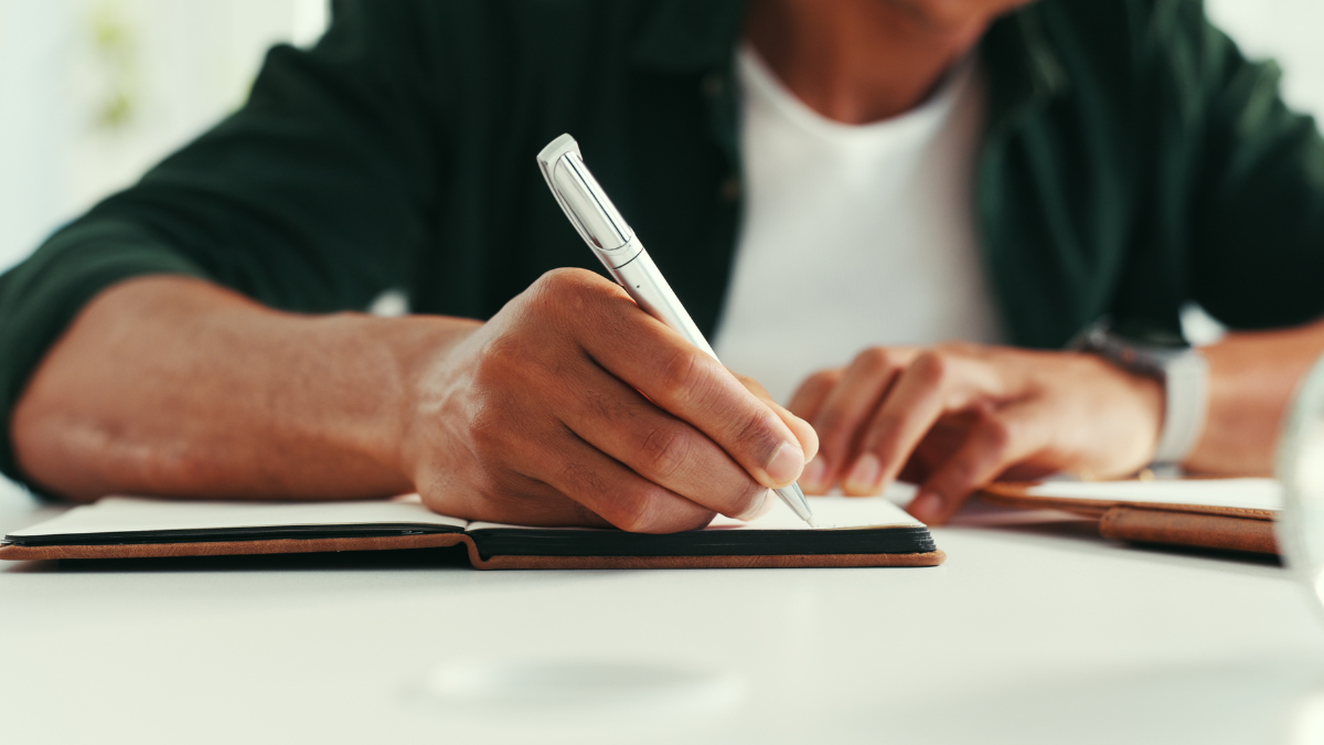 Pessoa escrevendo em caderno durante preparação para concursos públicos de prefeituras em São Paulo e Paraná.