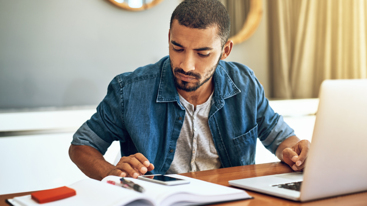 Candidato se prepara para concursos públicos com material de estudo e notebook.