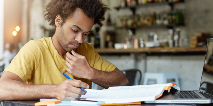 Pessoa estudando para concursos públicos com material de preparação e notebook, representando candidatos em busca de oportunidades no serviço público.