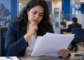 Mulher analisando documentos em ambiente bancário, representando os concursos bancários previstos para 2026.