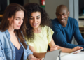 Pessoas estudando em grupo com notebook e materiais de preparação para concursos públicos.