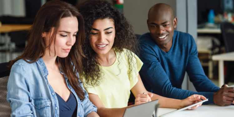 Pessoas estudando em grupo com notebook e materiais de preparação para concursos públicos.