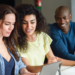 Pessoas estudando em grupo com notebook e materiais de preparação para concursos públicos.