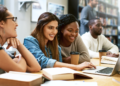 Candidatos estudando com notebook e materiais de apoio para concursos públicos.