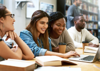 Candidatos estudando com notebook e materiais de apoio para concursos públicos.