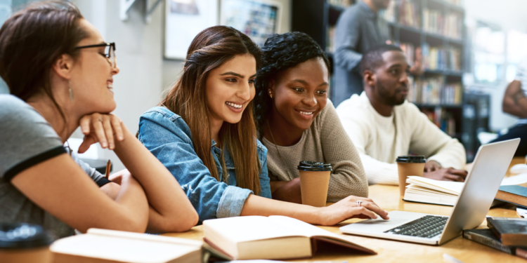 Candidatos estudando com notebook e materiais de apoio para concursos públicos.