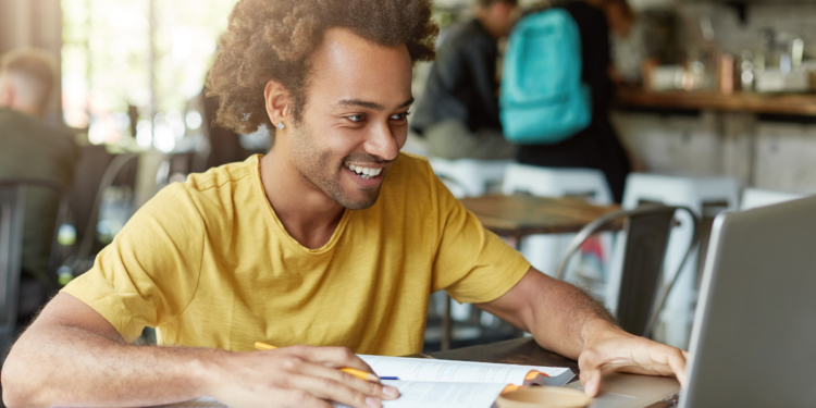 Pessoa estudando para concursos públicos com notebook e materiais de preparação.