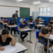 Candidatos realizam prova de concurso público em sala de aula de escola pública.