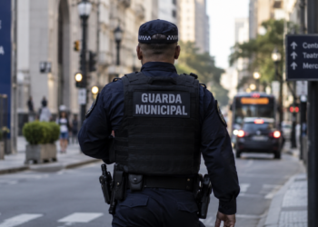 Guarda municipal de costas durante patrulhamento no centro de uma cidade.
