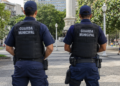 Dois guardas municipais de costas em praça pública representam concursos com vagas abertas em setembro.
