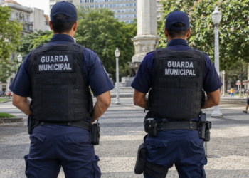 Dois guardas municipais de costas em praça pública representam concursos com vagas abertas em setembro.