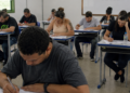 Candidatos realizam prova de concurso público em sala de aula durante processo seletivo municipal.