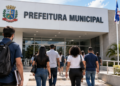 Pessoas se dirigindo a uma prefeitura municipal, representando candidatos interessados em concursos públicos e oportunidades no serviço público.