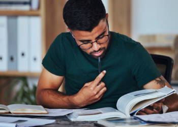 Estudante se preparando para concursos públicos com livros e materiais de estudo.