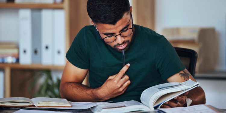 Estudante se preparando para concursos públicos com livros e materiais de estudo.