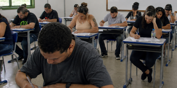 Candidatos realizam prova de concurso público em sala de aula durante processo seletivo municipal.