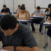 Candidatos realizam prova de concurso público em sala de aula durante processo seletivo municipal.