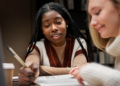 Pessoas estudando com livros e notebook para preparação para concursos públicos.