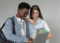 Estudantes consultam informações em notebook representando concursos públicos com inscrições abertas.