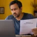 Homem consulta notebook enquanto segura documento sobre a malha fina do Imposto de Renda 2026