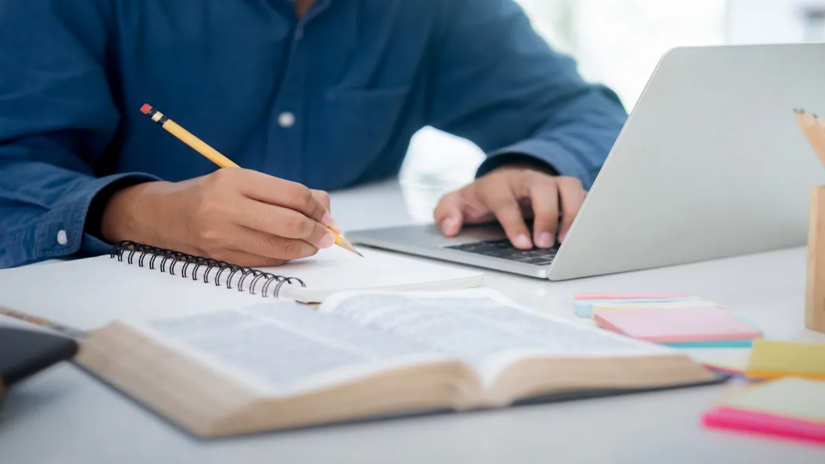 Candidato estudando com notebook e materiais de apoio para aprimorar a preparação para concursos.