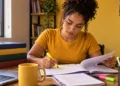 Estudante organiza os estudos para concursos administrativos com apostilas e marca-texto em mesa de preparação