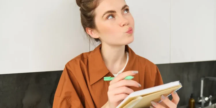 Mulher escreve em caderno enquanto representa dúvida sobre o uso das palavras doze e dose na língua portuguesa.