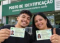 Jovem e mulher exibem documentos de identidade em frente a posto de identificação no Espírito Santo