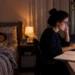 Mãe concurseira estudando no computador enquanto o filho dorme, representando a conciliação entre estudos e maternidade.