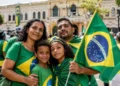 Família brasileira com bandeira nacional em espaço público, representando o feriado da Independência do Brasil.